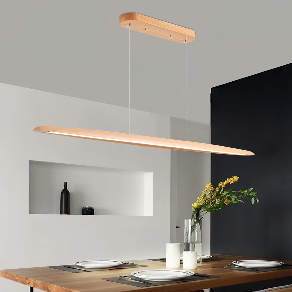 A Clérachic beech pendant glows along its underside above a live-edge dining table set with plates, in a grey room with a niche.