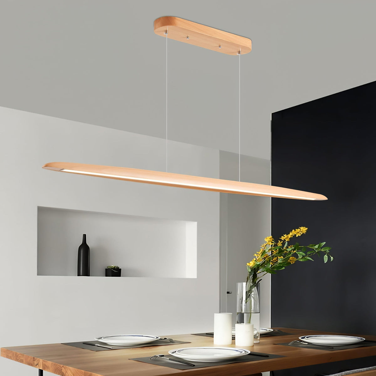 A Clérachic beech pendant glows along its underside above a live-edge dining table set with plates, in a grey room with a niche.