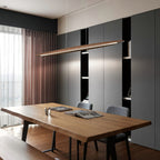 Above a live-edge wooden table with open magazines, a Clérachic wood pendant casts light in front of a grey storage wall.