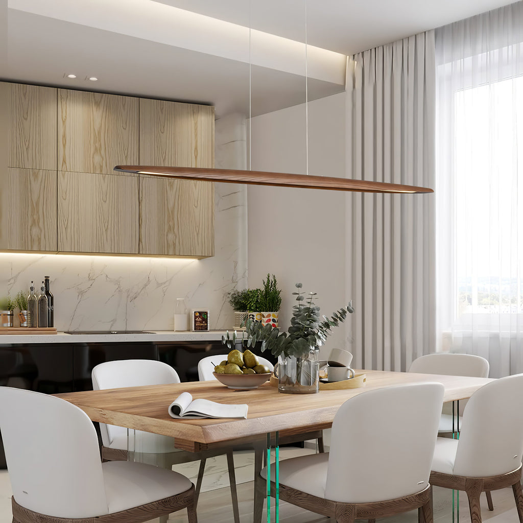 A Clérachic wood pendant runs across a bright kitchen dining area, above a timber table with white curved chairs.