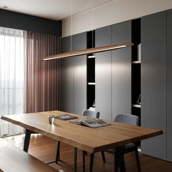 Viewed from a different angle, a Clérachic wood pendant lights a live-edge table in front of a dark grey wall of cabinets.