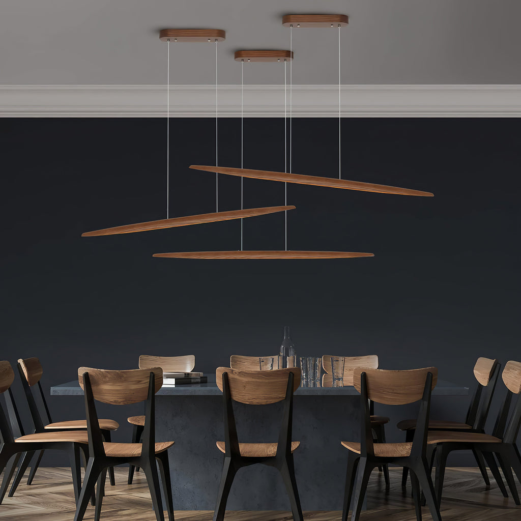 Three Clérachic wood pendants hang at different angles and heights above a dining table, against a deep navy wall.
