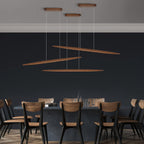 Three Clérachic wood pendants hang at different angles and heights above a dining table, against a deep navy wall.