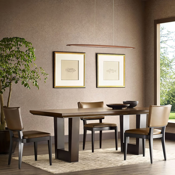 A thin walnut-toned Clérachic pendant hangs above a dark dining table with leather chairs and two framed prints.