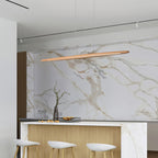 Above a marble-backed kitchen island with white stools, a Clérachic beech pendant hangs against a veined stone wall.