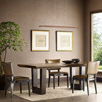 A narrow, dark walnut Clérachic pendant hangs in a taupe dining room with leather chairs and a green tree by the window.