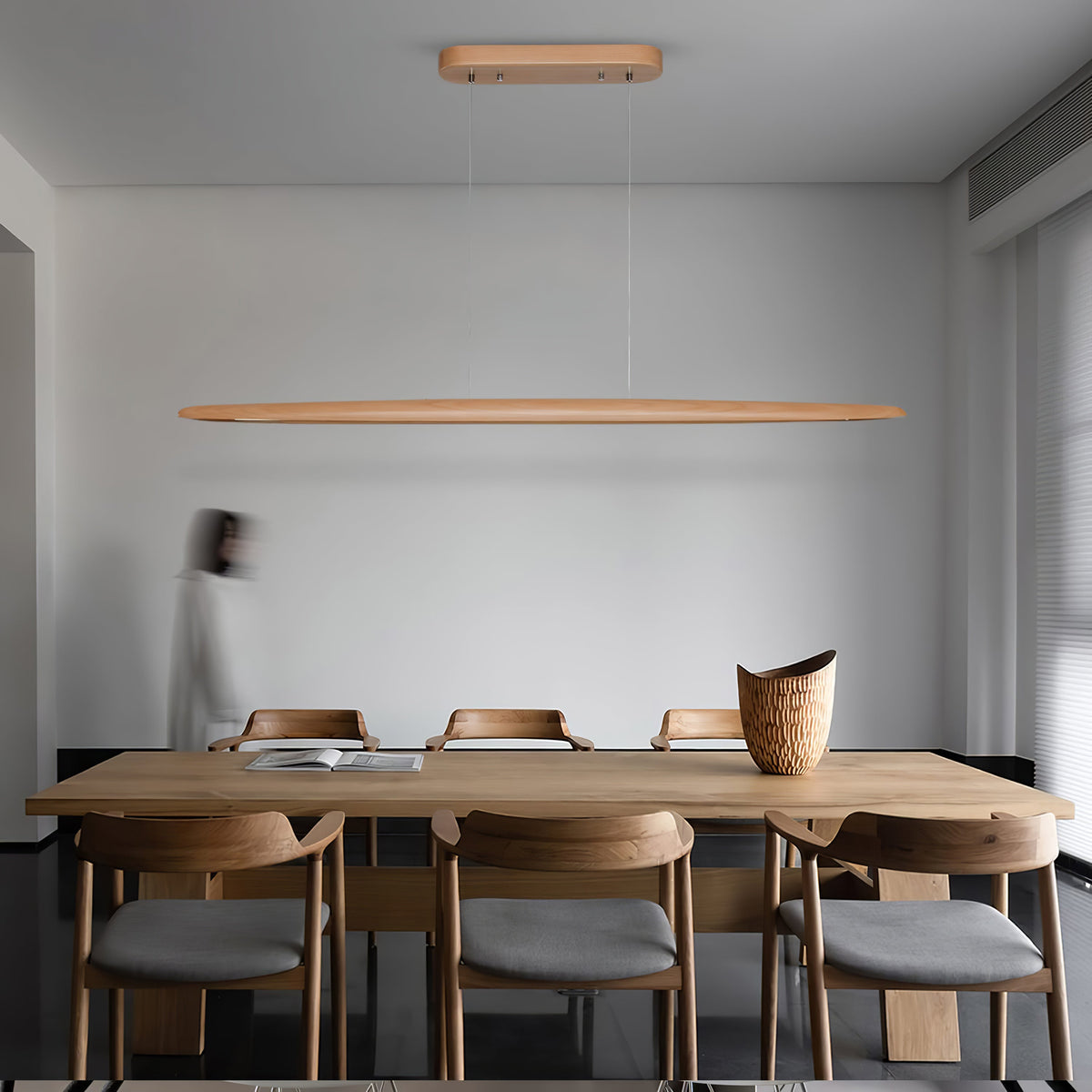 A Clérachic beech pendant hangs from its wooden canopy above a long timber table in a pale grey dining room.