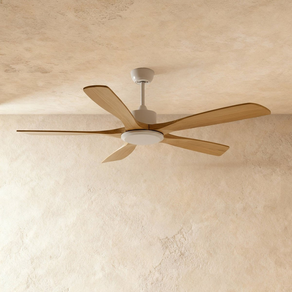 Clérachic five-blade ceiling fan with pale wood blades and a white motor housing and round light, against a warm plaster ceiling.