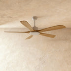 Clérachic five-blade ceiling fan with pale wood blades and a white motor housing and round light, against a warm plaster ceiling.