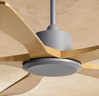 Close view of the Clérachic fan's grey motor housing, silver-grey light disc and curved pale wood blade roots under a plaster ceiling.