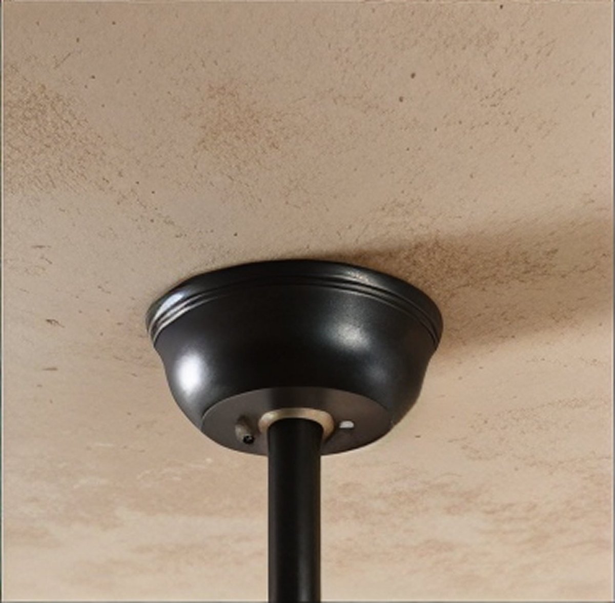 Clérachic fan's black ceiling canopy with a trimmed rim and a black downrod fixed to a textured plaster ceiling.