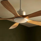 Clérachic ceiling fan in white and pale wood seen from below, showing its round light disc and curved blades in soft side light.