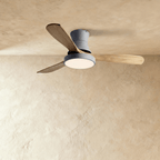 Clérachic low-profile ceiling fan in grey with three natural wood blades and its round LED light glowing warmly.