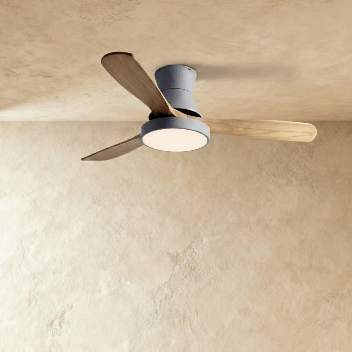 Clérachic low-profile ceiling fan in grey with three natural wood blades and its round LED light glowing warmly.