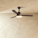 Clérachic ceiling fan on a black downrod with three dark walnut-toned blades and its round LED light switched on.