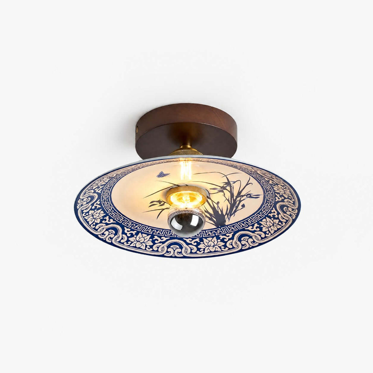 This Clérachic ceiling light on a plain white backdrop, with a dark wood canopy and a blue-and-white ceramic shade.