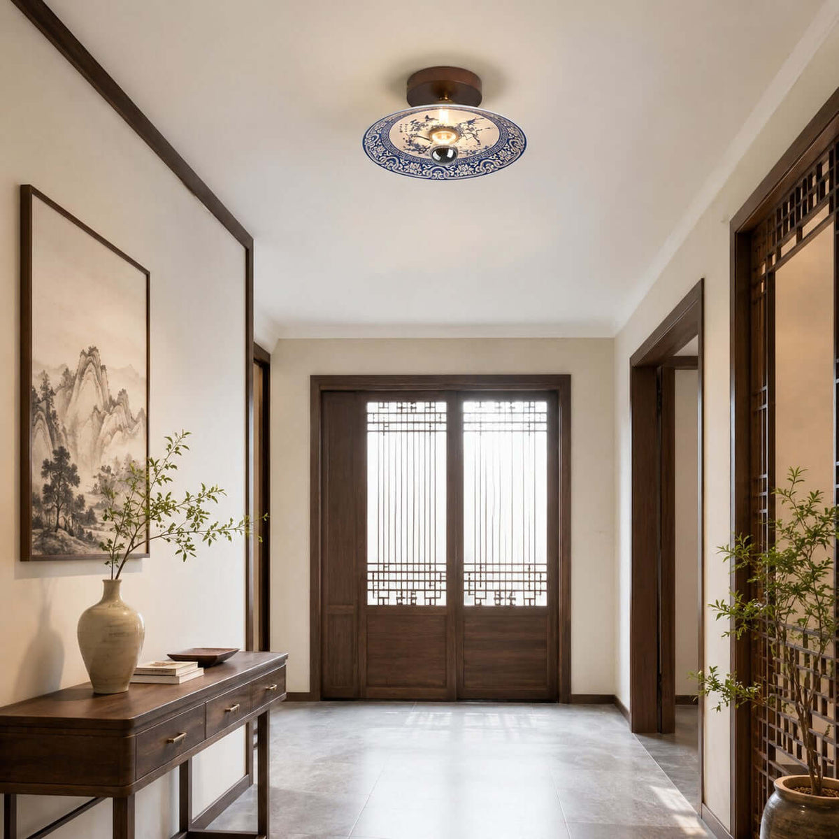 A Clérachic ceiling light hangs in a calm entry hall with a dark console table, a tall vase and a framed landscape print.
