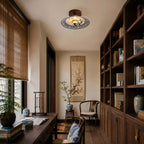 A Clérachic ceiling light in a study with a dark wood bookcase, a writing desk and a bamboo blind at the window.