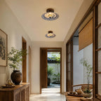 Two Clérachic ceiling lights, one behind the other, in a corridor with wood-framed doors and a view of a garden.