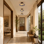Three Clérachic ceiling lights run in a line down a long, bright hallway beside tall windows and a wooden bench.