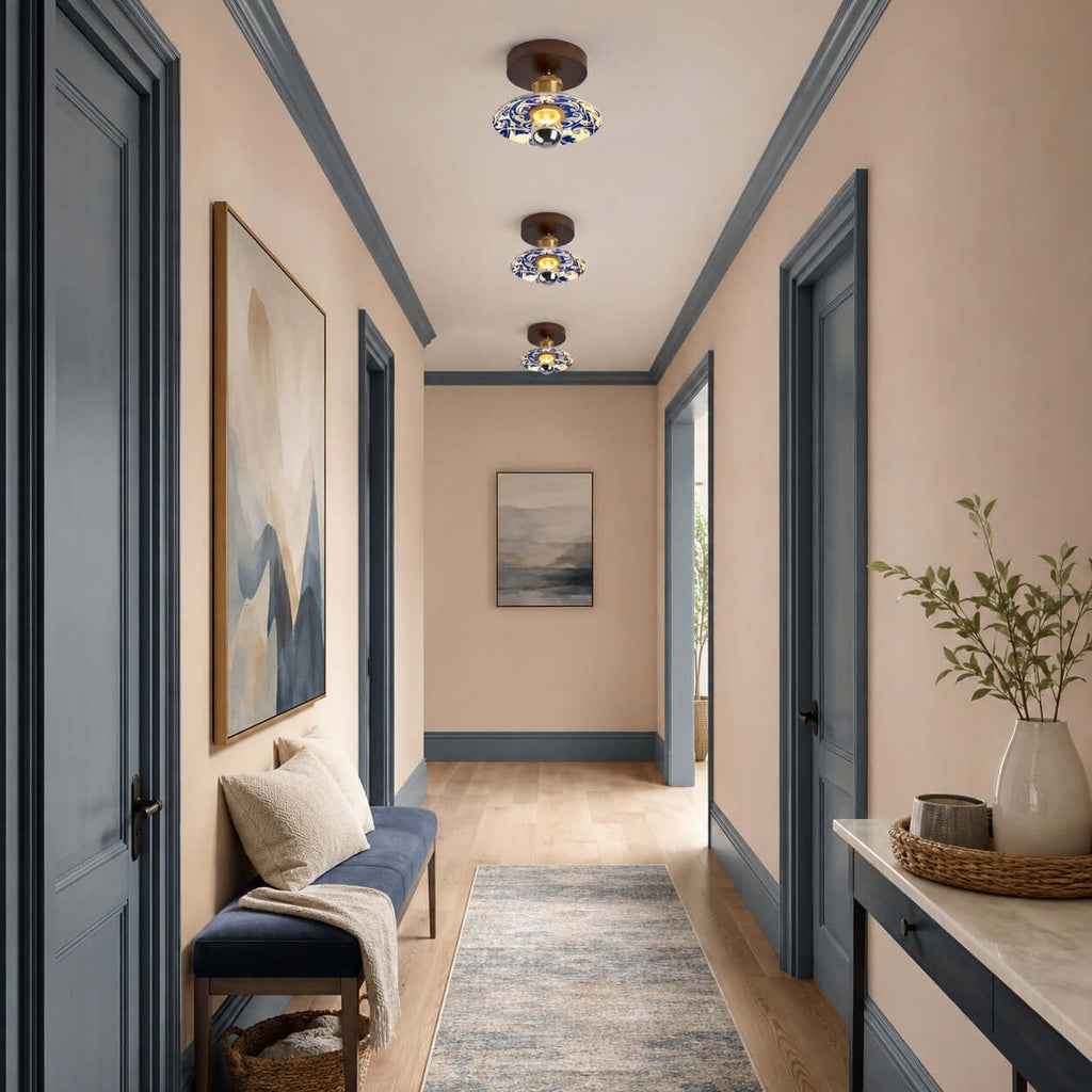 A line of three Clérachic ceiling lights along a peach-walled hallway with blue door frames and a patterned runner.