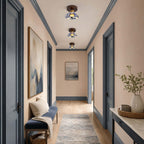 A line of three Clérachic ceiling lights along a peach-walled hallway with blue door frames and a patterned runner.