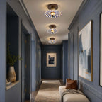 Three Clérachic ceiling lights lead down a dark blue hallway, with a large abstract painting and a cream bench.