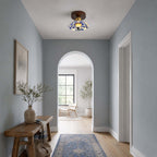 A Clérachic ceiling light in a pale blue hallway with an arched opening, a wooden bench and a vase of branches.