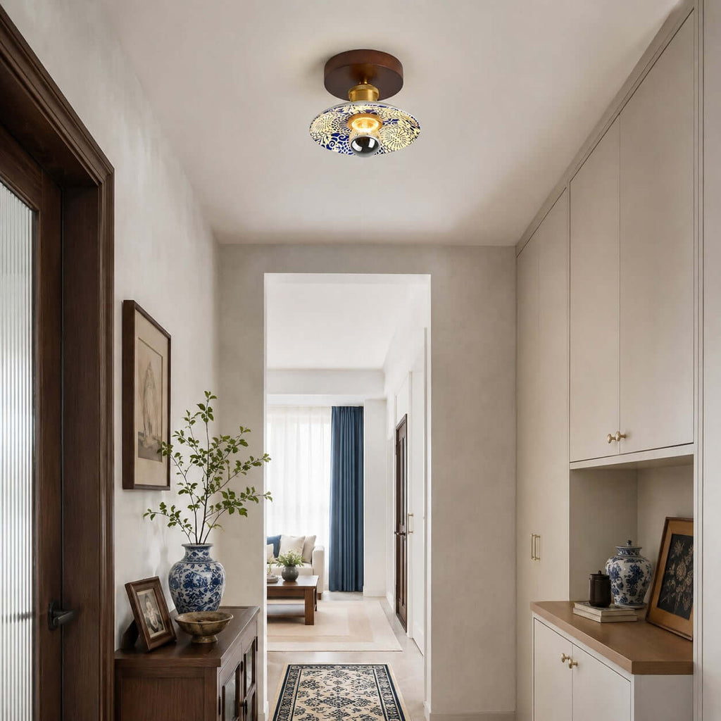 A Clérachic ceiling light with a patterned shade in a cream hallway with built-in cabinets and a blue-and-white vase.