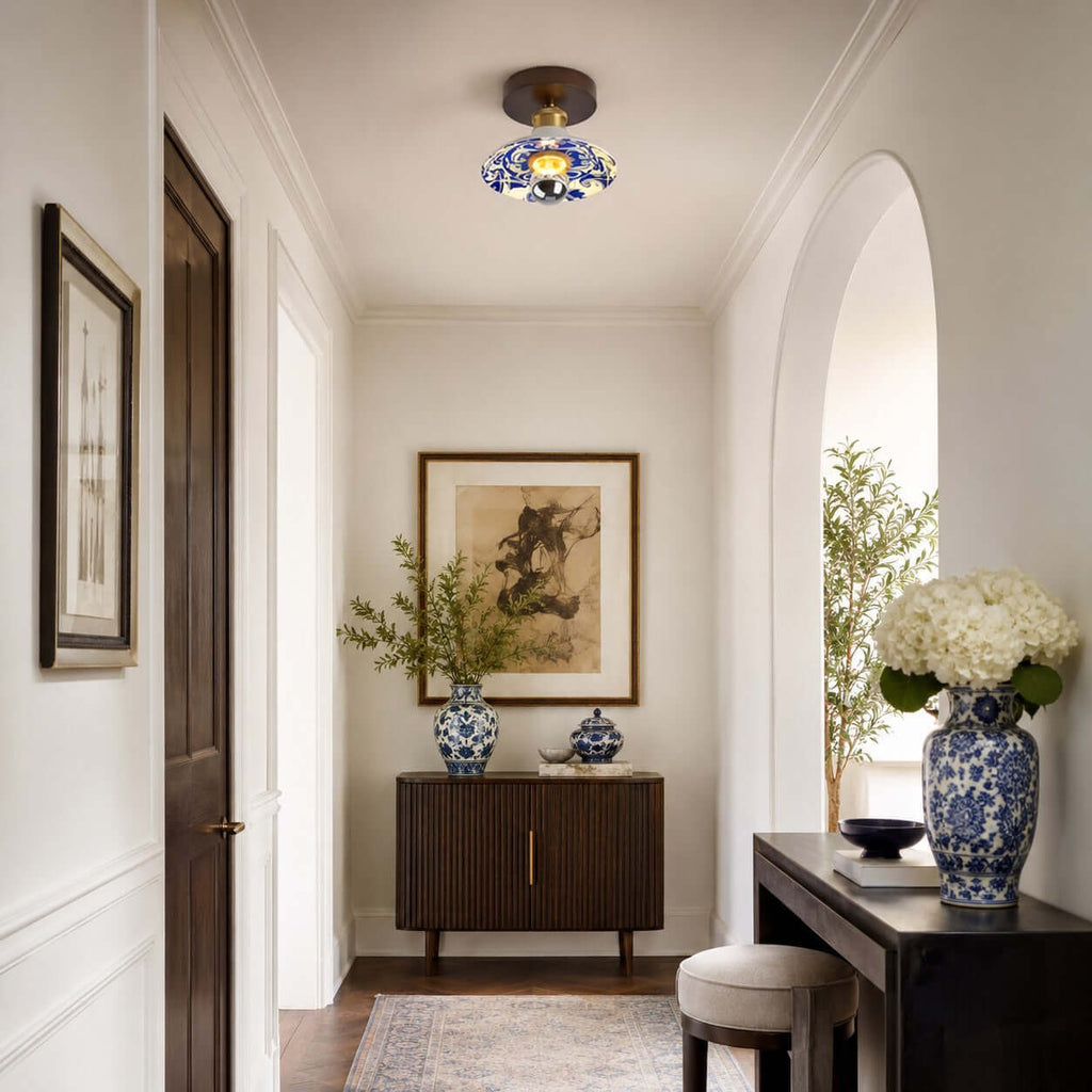 A Clérachic ceiling light above an arched entry with a dark sideboard and a large vase of white hydrangeas.