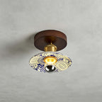 A Clérachic ceiling light with a cream shade patterned in blue and yellow, a round wood canopy and a brass fitting above.