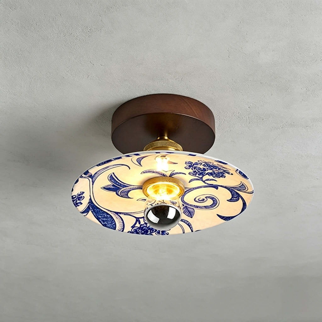 This Clérachic ceiling light has a wide shade painted with blue scrolls and flowers, under a round wood canopy.