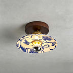 This Clérachic ceiling light has a wide shade painted with blue scrolls and flowers, under a round wood canopy.