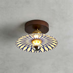 A Clérachic ceiling light with a sunburst of blue lines across its cream shade, fixed to the ceiling by a round wood canopy.