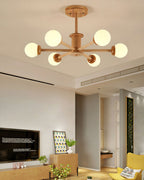Lit six-globe ceiling light in light wood from Clérachic, above a living room with a wooden sideboard and a yellow armchair.