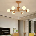 Six frosted globes lit warm on pale wooden arms, a Clérachic ceiling light in a room with a wall-mounted television.