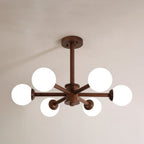Walnut Clérachic ceiling light seen from below, with six white globes on dark wooden arms, against a soft taupe ceiling.