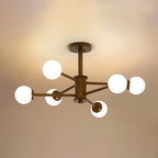 Walnut Clérachic ceiling light with eight white globes on slim dark arms, lit against a warm tan ceiling.