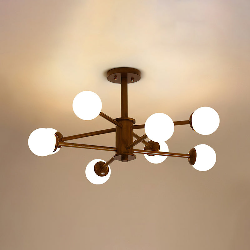 Dark walnut Clérachic ceiling light with eight white globes on long thin arms, lit against a golden ceiling.