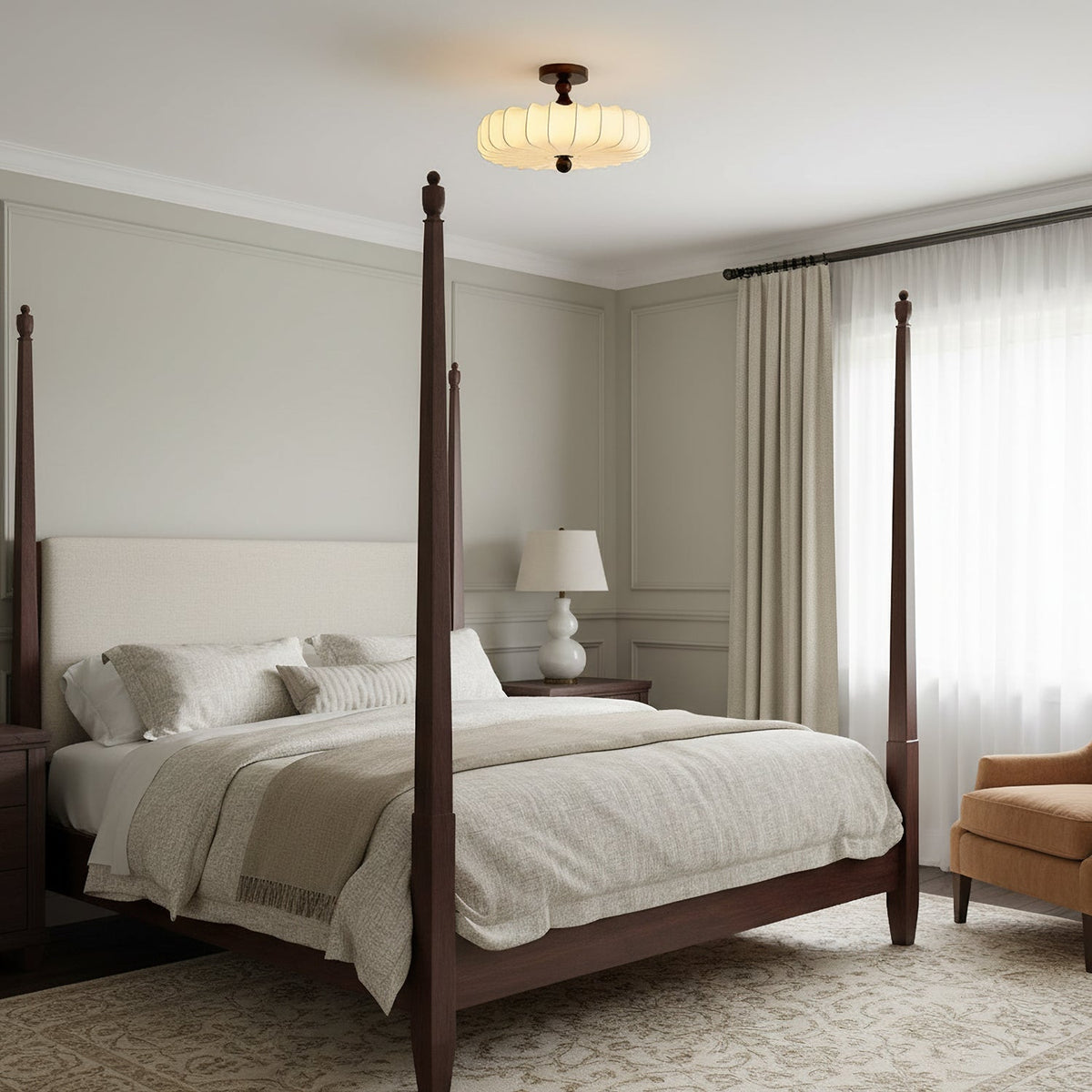 A small Clérachic ceiling light with a pale pleated shade hangs high above a four-poster bed in a calm grey-beige bedroom.