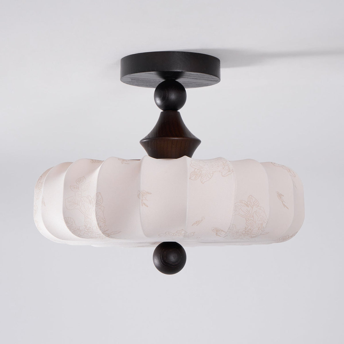 An unlit Clérachic ceiling light on a grey backdrop, showing the pleated beige drum, turned dark stem and ball finial below.