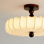 Close view of the broad pleated shade on this Clérachic ceiling light, with a dark walnut-colour canopy, turned stem and round wooden finial.