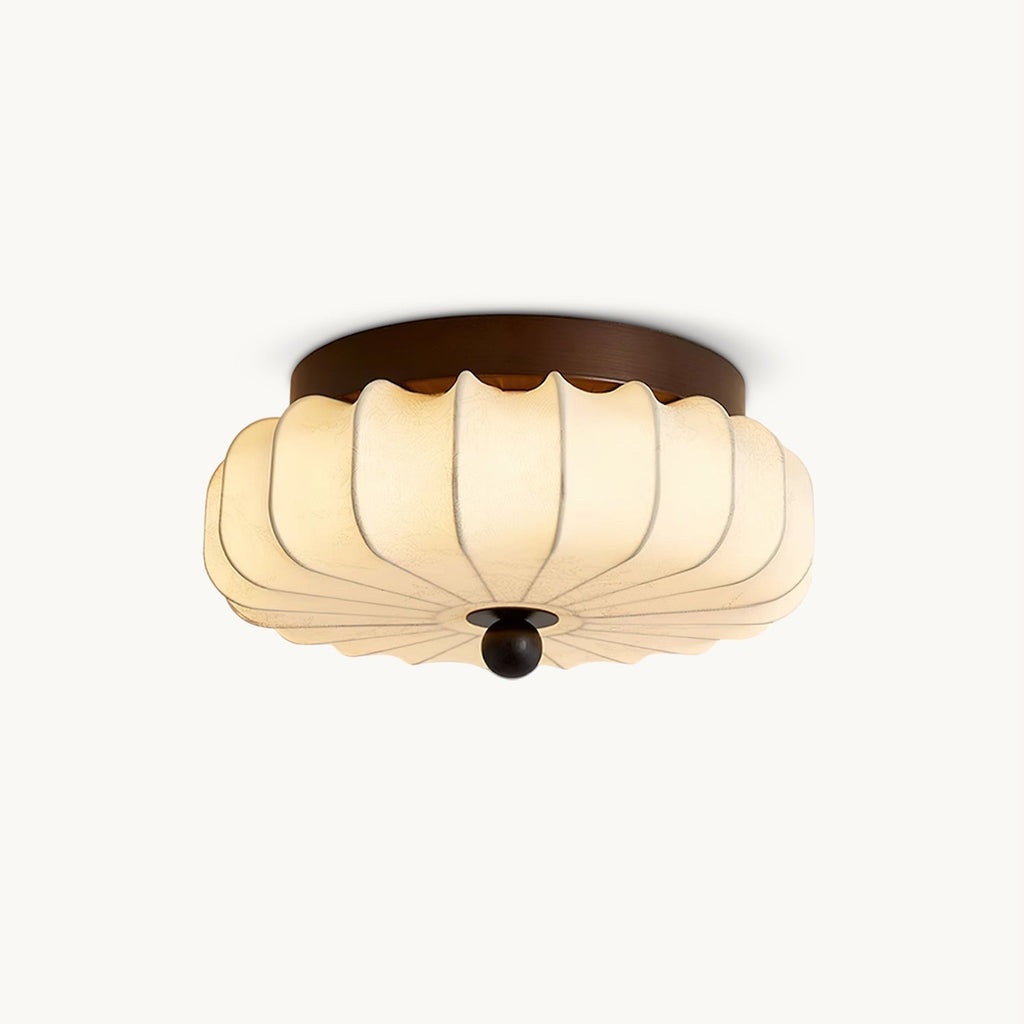 A pleated fabric Clérachic ceiling light, with a dark walnut-coloured frame and a wooden ball at the centre, on white.