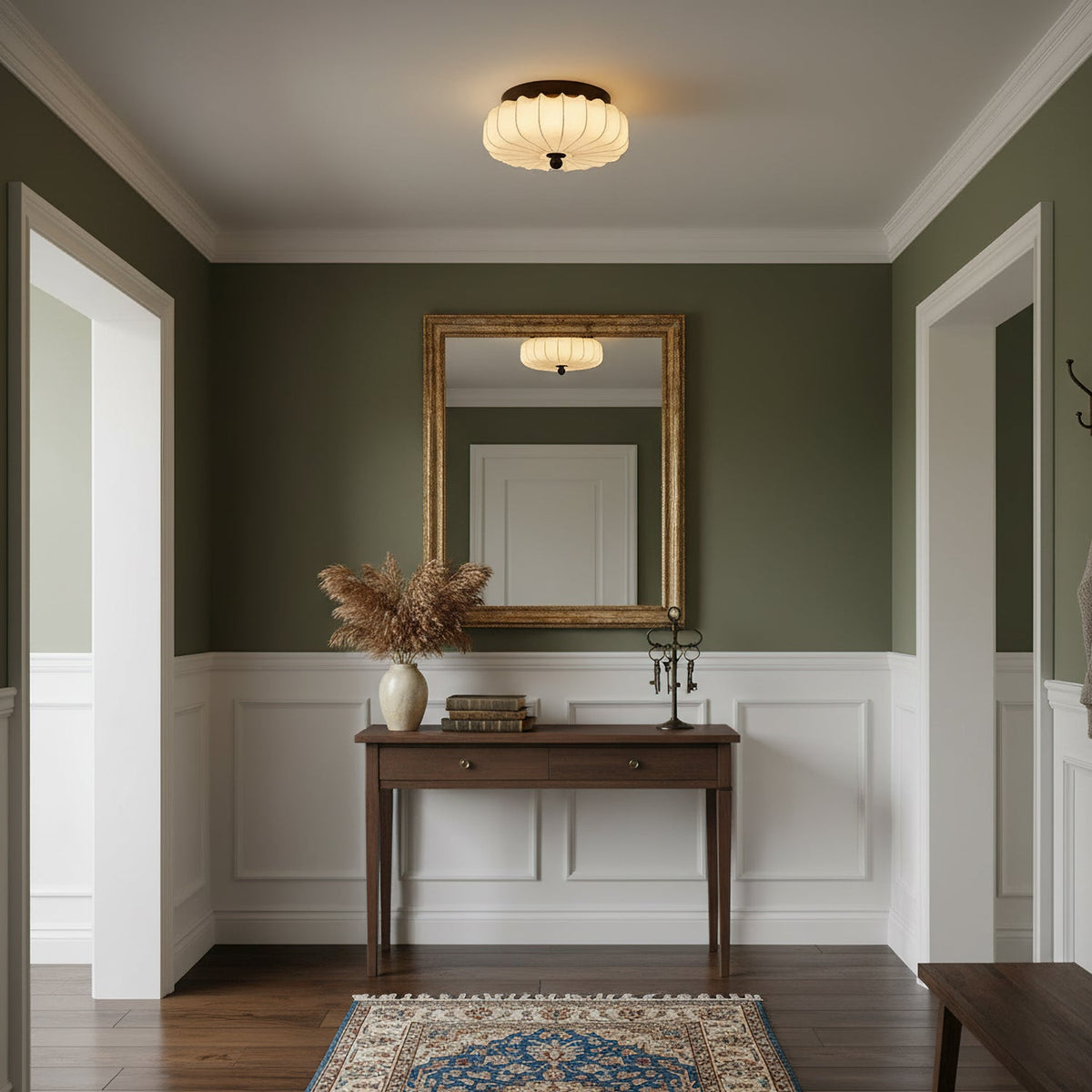 Over a hallway with olive walls, a gilt mirror and a wooden console, this pleated Clérachic ceiling light gives a warm glow.