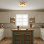 Over a cream kitchen with a green island and two wooden stools, this pleated fabric Clérachic ceiling light is lit.