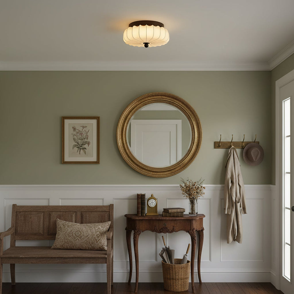 In an entrance hall with a round gilt mirror, a wooden bench and a coat hook, this pleated Clérachic ceiling light is lit.