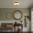 In an entrance hall with a round gilt mirror, a wooden bench and a coat hook, this pleated Clérachic ceiling light is lit.