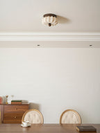 A pleated Clérachic ceiling light, unlit, above a dining room with a sideboard, a table and button-backed chairs.
