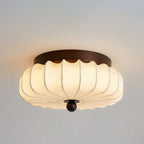 Close view of the ribbed fabric shade and dark frame of this Clérachic ceiling light, lit, against a grey ceiling.