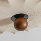 Close view of the walnut ball and a faint floral print on the fabric of this Clérachic ceiling light.